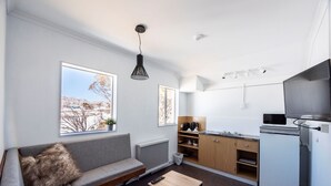 Un salon moderne comprenant un canapé, une petite table et un coin cuisine avec des placards et des appareils électroménagers.