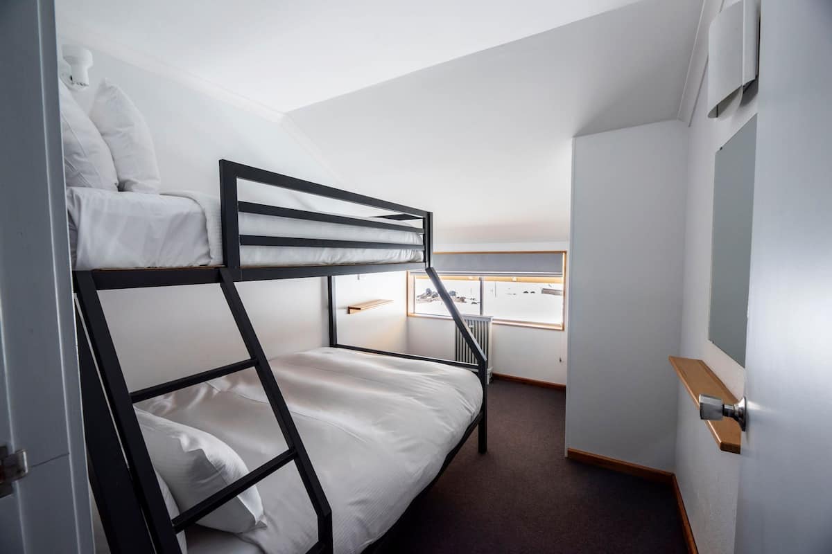 A bunk bed room with a window and a door.