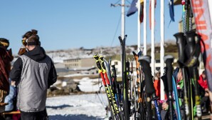 A row of skis and snowboards leaning against a wall, with a clear sky in the background. - Eiger Chalet (Perisher Valley)