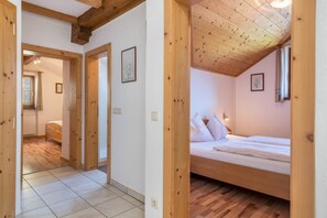 Quarto com teto de madeira, uma cama e janela com cortinas.