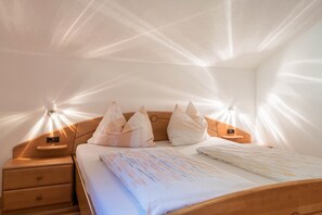 Un lit bien fait, avec une couvre-lit à motifs, deux tables de chevet avec des lampes et une tête de lit en bois.