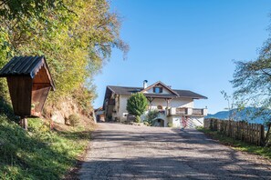 Une maison avec une allée en gravier, une clôture en bois et une vue sur les montagnes.