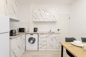 Ett kompakt kök med tvättmaskin, mikrovågsugn, brödrost och diskho.