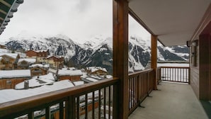 Ein Holzbalkon mit Blick auf schneebedeckte Häuser und Berge.