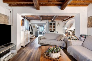 A living room with a sofa, a TV, and a wooden coffee table with a basket. - Holiday Home 'Casa Collicello Relax' with Mountain View, Private Pool & Wi-Fi (Camaiore)