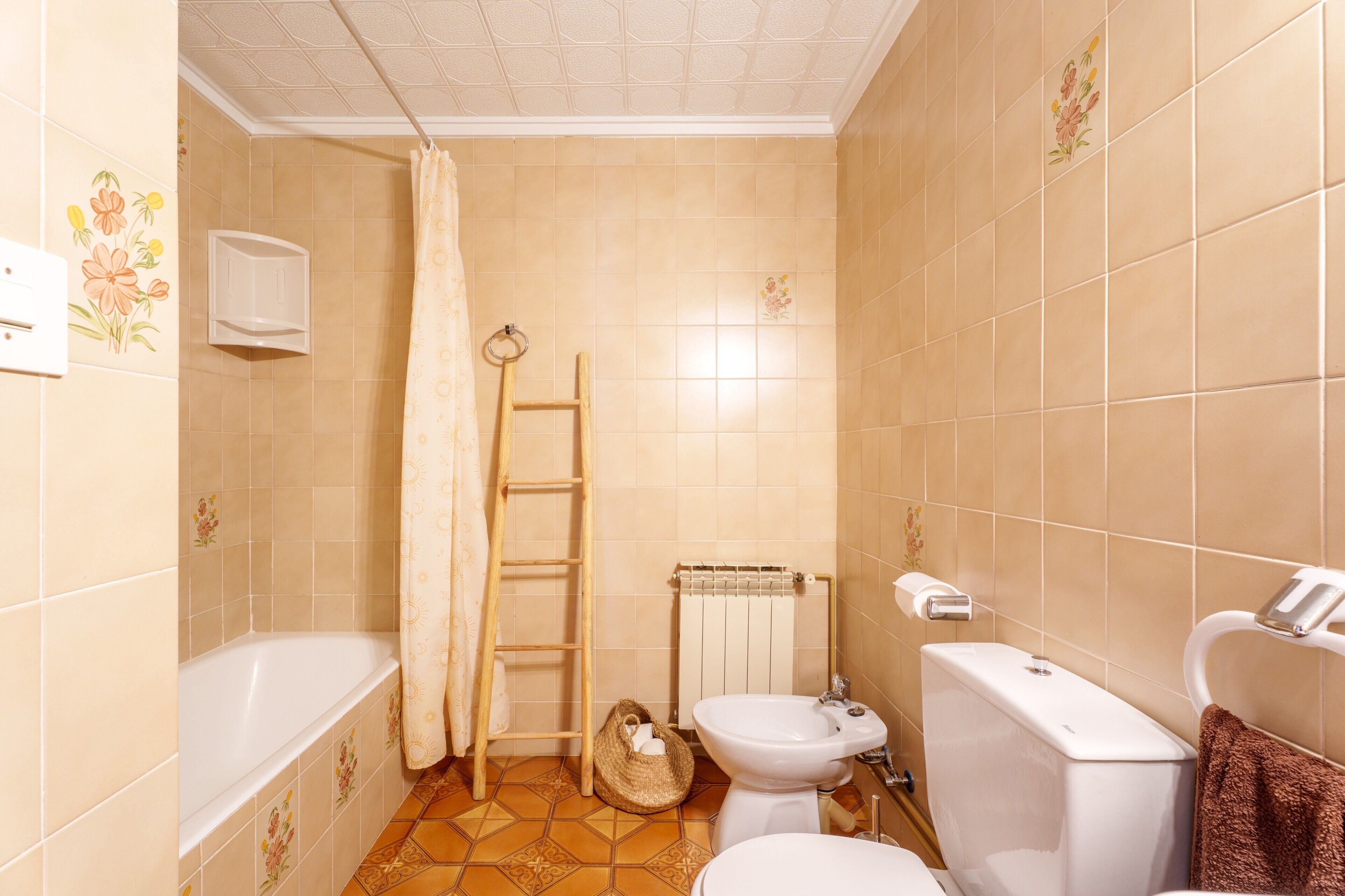 Un baño con bañera, inodoro, bidé y un perchero para toallas.