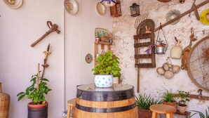 Un intérieur rustique agrémenté d’une barrique en bois, de plantes en pot et de divers ustensiles de cuisine accrochés au mur.
