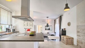 Une cuisine moderne dotée d’un îlot central, de meubles blancs et d’un coin repas avec une table et des chaises.