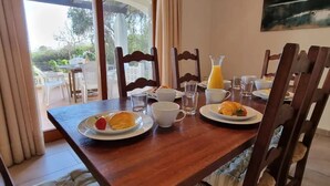 A breakfast table with plates of food, glasses, and a jug of orange juice.