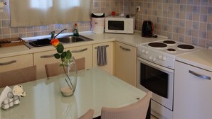 A kitchen with a dining table, chairs, a microwave, stove, and a sink. - Apartment In A Hotel 'Anemi Leros 2' with Sea View, Wi-Fi and Air Conditioning (Leros)