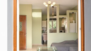 Una sala de estar con una mesa de centro de vidrio, un sofá y una puerta que da a una cocina.