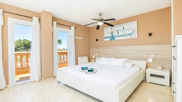 A bedroom with a large bed, a ceiling fan, a nightstand, and a painting on the wall.