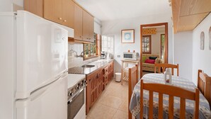 A kitchen with wooden cabinets, a white refrigerator, a stove, and a dining table with chairs.