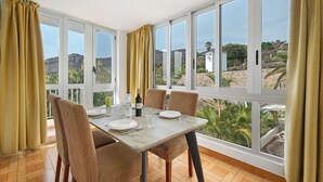 A dining area with a table set for four, large windows, and a view of the landscape.