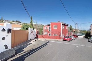A street with a red building, parked cars, and a clear blue sky.