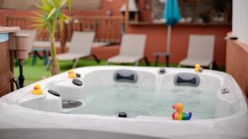 Un jacuzzi con patitos de goma y un patio con sillas y una palmera.