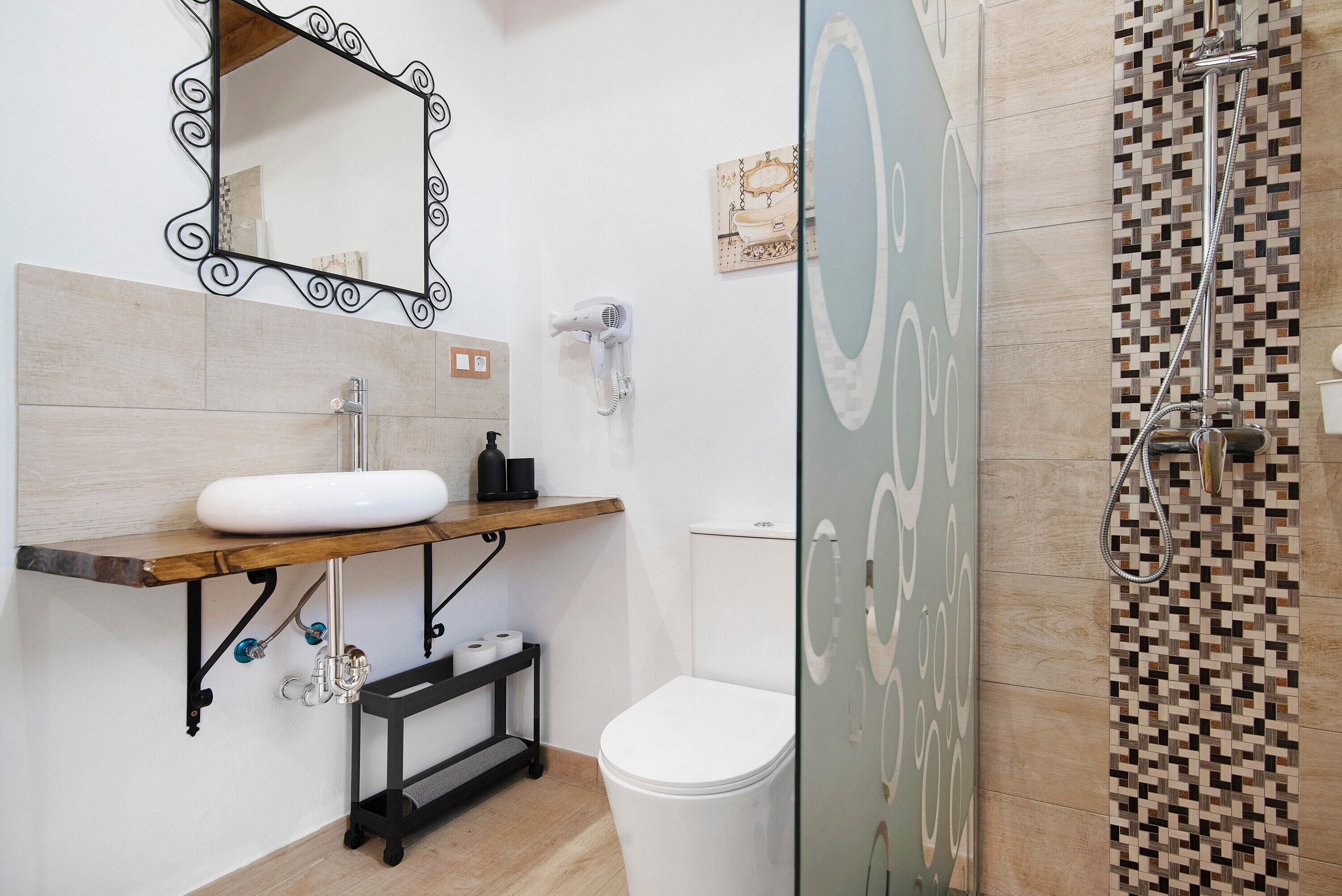 Un baño con lavamanos blanco, espejo, inodoro y zona de ducha.