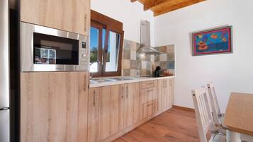 Una cocina moderna con muebles de madera, un microondas de acero inoxidable y un ventanal.