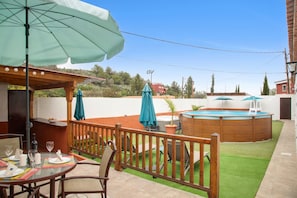 A patio area with a pool, outdoor seating, and a wooden deck.