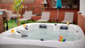 Ein Whirlpool mit Gummiducken, umgeben von Liegestühlen und einer Palme.