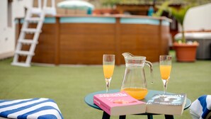 Eine Terrasse mit Tisch, zwei Büchern, zwei Orangensaftgläsern und einer Saftkanne.