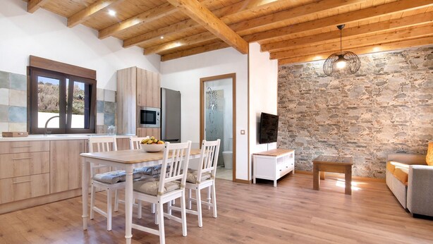 Eine moderne Küche mit Holzausbau, einem Esstisch mit Stühlen, einer Steinwand und einem Fernseher.