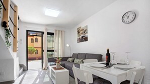 Een moderne woonkamer met een bank, eettafel en een klok aan de muur.