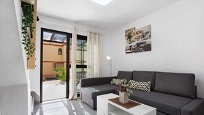 Een moderne woonkamer met een grijze bank, een witte salontafel en een raam in de volle hoogte met gordijnen.