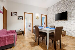 Un coin repas avec un mur en briques, un téléviseur à écran plat et une table à manger dressée avec des assiettes et des verres.