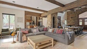 A spacious living room with a large sectional sofa, a coffee table, and a stone fireplace. - The Meadowbrook, games, BBQ, huge back yard (Big Bear City)