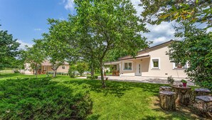 A residential property with a well-maintained lawn, a patio area, and a house with a tiled roof. - Nice home in Svetvincenat (Svetvincenat)