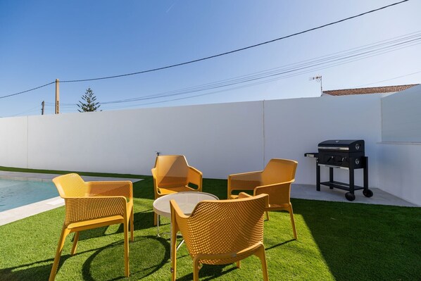 Un patio con mobiliario exterior y una parrilla.