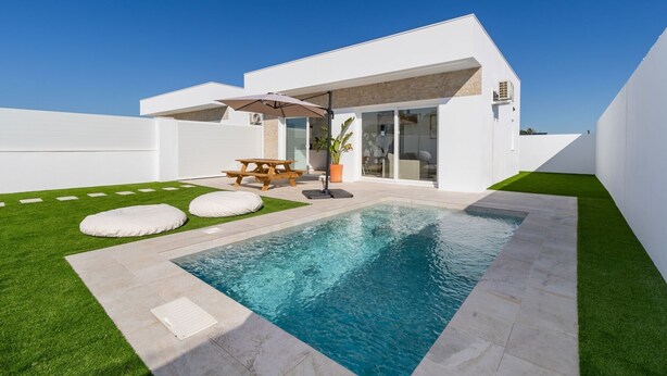 Een modern huis met een zwembad, een terras met tafel en stoelen, en een verzorgd gazon.