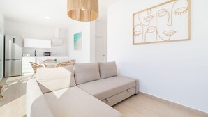Un salon moderne avec un canapé d’angle, un luminaire suspendu et une œuvre d’art murale.