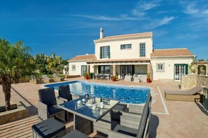 Une maison à deux étages dotée d’une piscine, de mobilier d’extérieur et d’un espace patio.
