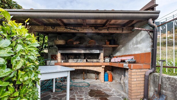An outdoor kitchen with a stone floor, a table, and a brick oven.