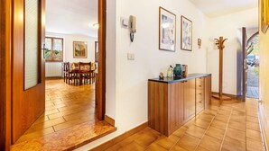 A hallway with wooden flooring, a wooden cabinet, and a door leading to a dining area.