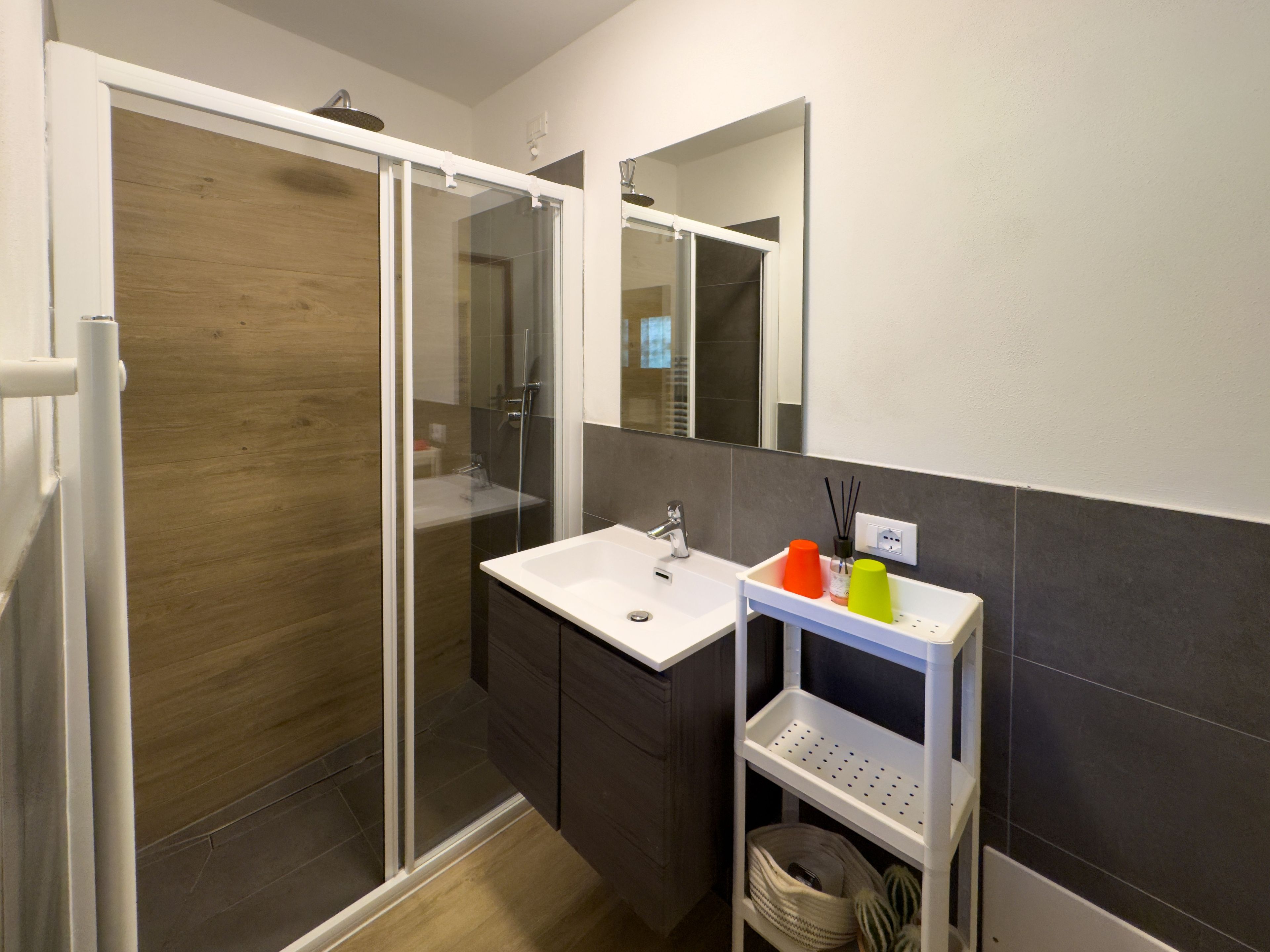 Une salle de bain moderne avec une douche à parois de verre, un lavabo blanc et un miroir au-dessus.