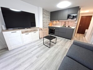 A compact living space with a kitchenette, a flat-screen TV, a sofa, and a coffee table.