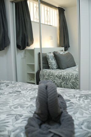 A bedroom with a bed, a wardrobe, and a window with curtains.