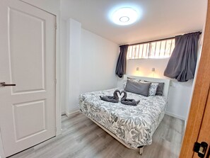 A bedroom with a bed, a door, a window with curtains, and a ceiling light. - Holiday Apartment 'En Playa De Las Americas' with Shared Pool, Private Terrace and Wi-Fi (Playa de Las Americas)