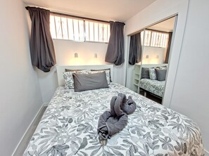 A bedroom with a bed, a mirror, and a window with curtains. - Holiday Apartment 'En Playa De Las Americas' with Shared Pool, Private Terrace and Wi-Fi (Playa de Las Americas)