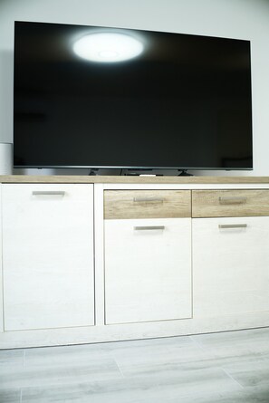 A flat-screen TV mounted on a white cabinet with a wooden accent. - Holiday Apartment 'En Playa De Las Americas' with Shared Pool, Private Terrace and Wi-Fi (Playa de Las Americas)
