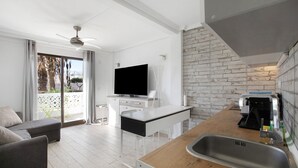 A modern kitchen with a TV, a dining area, and a balcony with a view. - Holiday Apartment 'En Playa De Las Americas' with Shared Pool, Private Terrace and Wi-Fi (Playa de Las Americas)