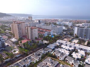 A coastal cityscape with high-rise buildings, a marina, and a clear view of the sea. - Holiday Apartment 'En Playa De Las Americas' with Shared Pool, Private Terrace and Wi-Fi (Playa de Las Americas)