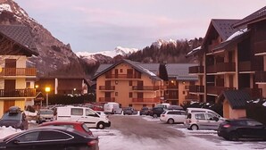 Ein Hotel mit mehreren Etagen, Balkonen und einem Parkplatz mit Autos.