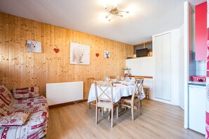 Une pièce chaleureuse avec un mur en bois, une table à manger dressée pour quatre personnes et un canapé.