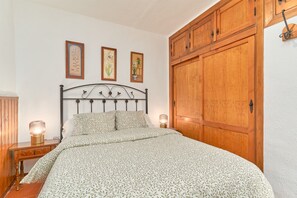 Une chambre à coucher avec un lit, une armoire en bois, des tableaux encadrés au mur et des lampes de chevet.