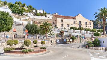 Una calle con una glorieta, edificios de piedra y una colina con casas blancas.