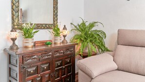 A wooden cabinet with decorative carvings, a mirror with a leaf pattern, and a sofa.